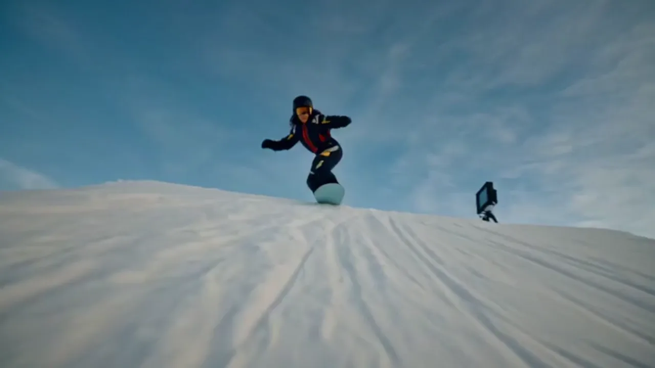 Red Bull Peach Edition spec action film — a snowboarder carving a sunlit slopestyle course under blue sky