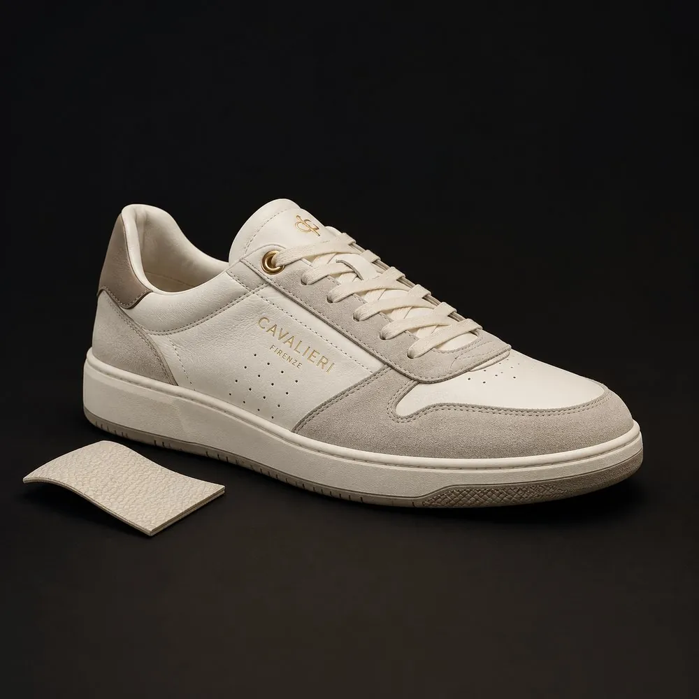 A cream leather sneaker lit on black beside a swatch of its pebbled leather